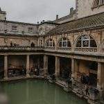 Băile Romane din Bath Anglia cu apa verde si arhitectura georgiană în fundal la apus