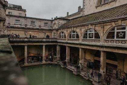 Băile Romane din Bath Anglia cu apa verde si arhitectura georgiană în fundal la apus