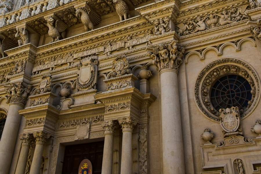 Detaliu sculptural al fațadei baroce a Basilicii Santa Croce din Lecce, cu ornamente în piatră lecceze aurie