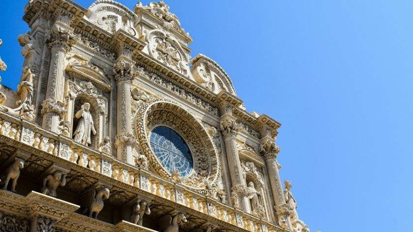 Fațada barocă aurie a Basilicii Santa Croce din Lecce, Puglia, Italia, luminată de soarele de amiază